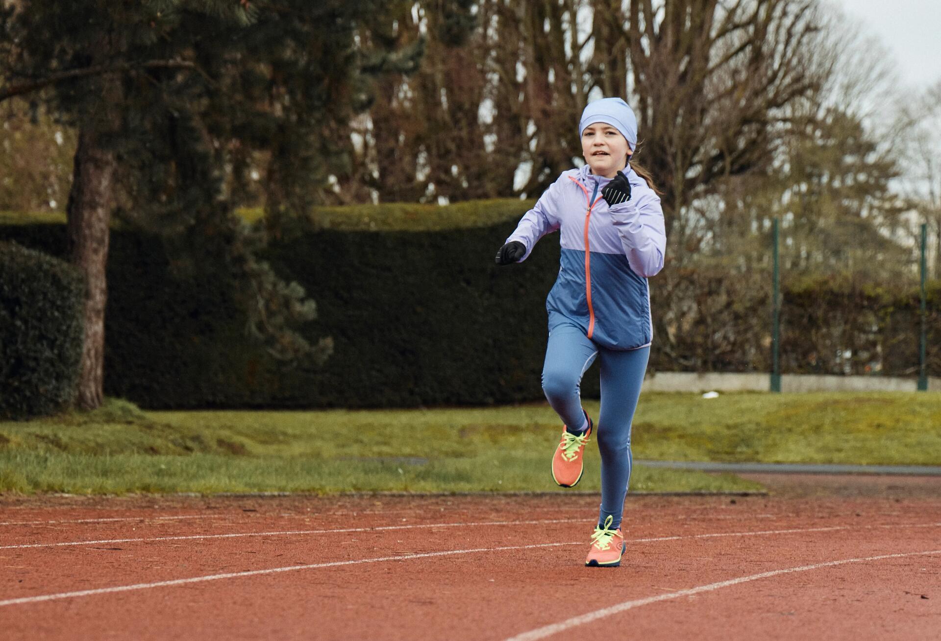 dziewczynka biegnąca po bieżni w odzieży biegowej i akcesoriach do biegania zimą 