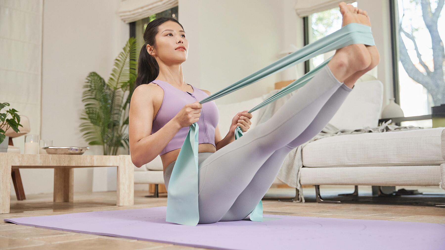 Kobieta w legginsach do pilatesu wykonująca ćwiczenia z użyciem gumy do ćwiczeń