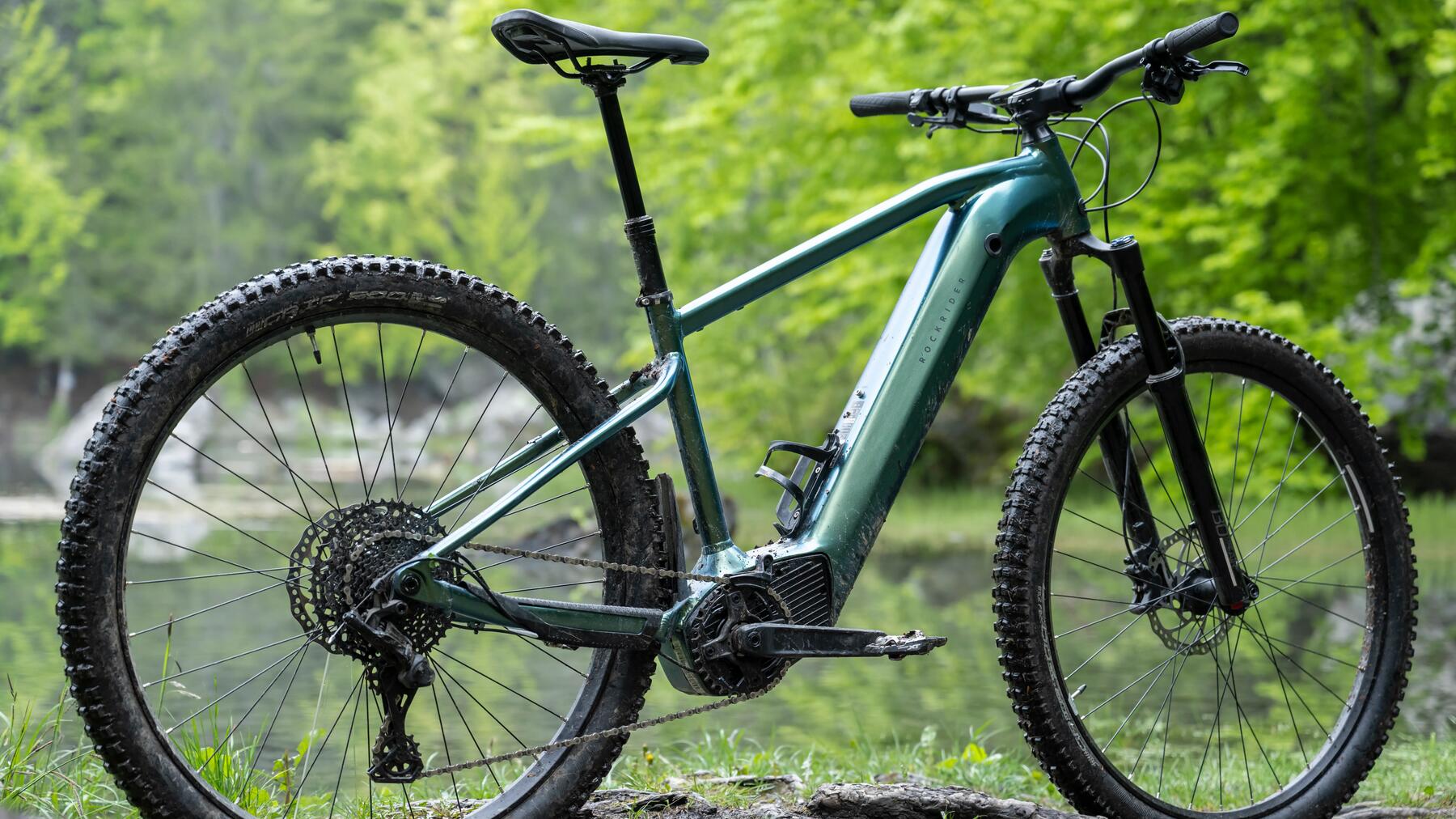 Türkises E-Bike steht vor einem See