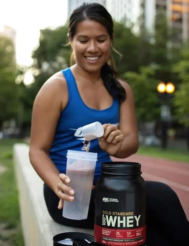 Kobieta przygotowująca shake'a z odżywką białkową aby zbudować masę mięśniową