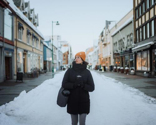 Kobieta w pomarańczowej czapce i czarnej kurtce idąca po mieście