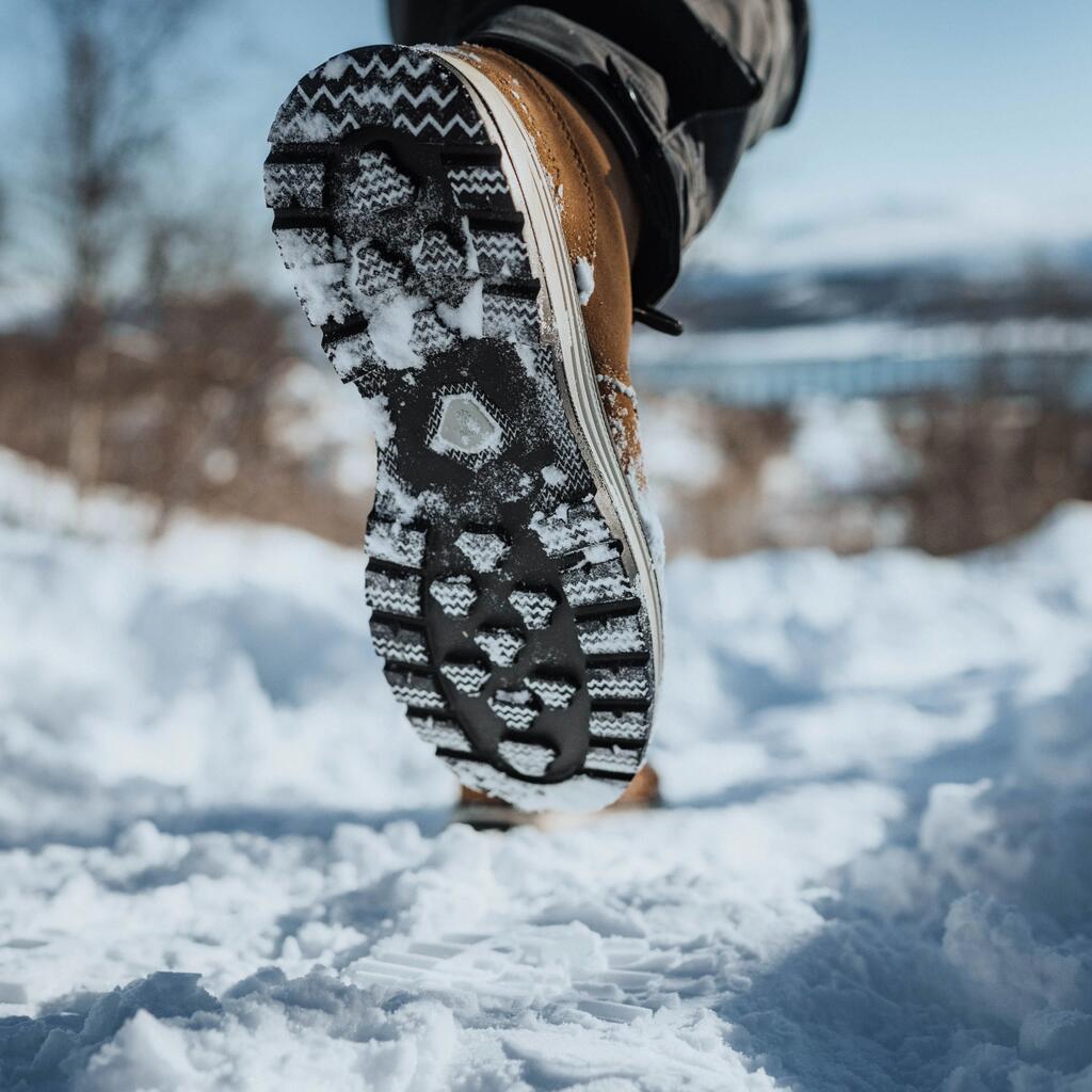 Man sieht die Unterseite eine Schuhs mit gutem Profil auf Schneeboden