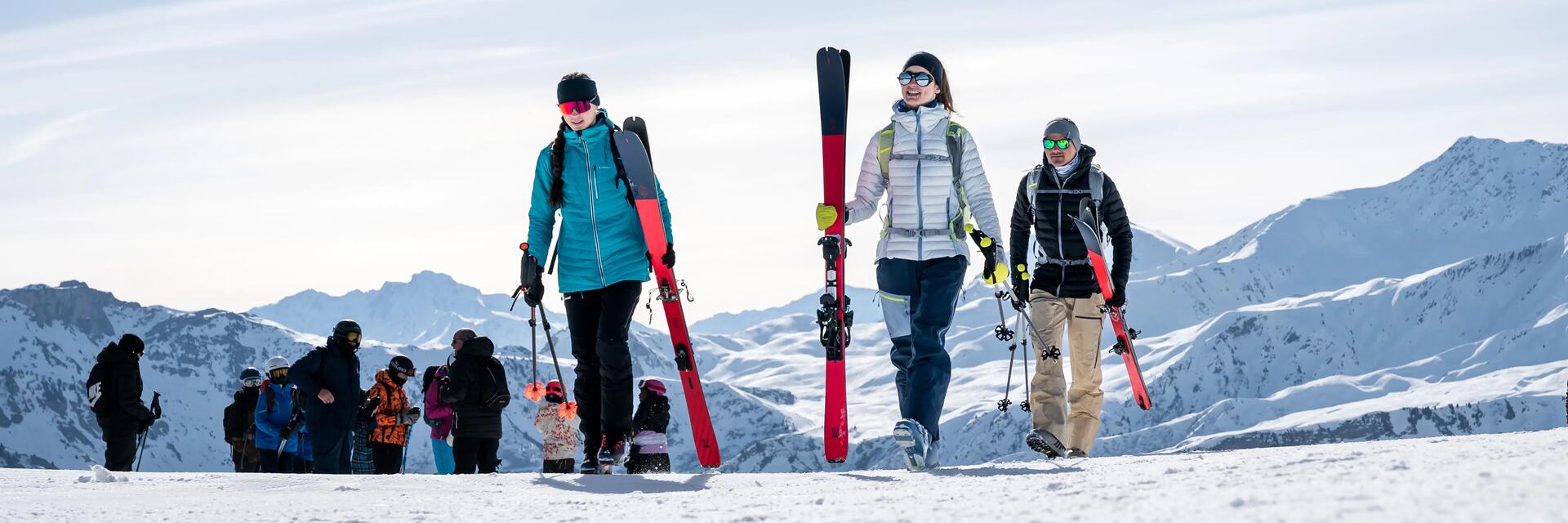 Narciarze idący na stoku trzymając kije narciarskie i narty dobrane do wzrostu 
