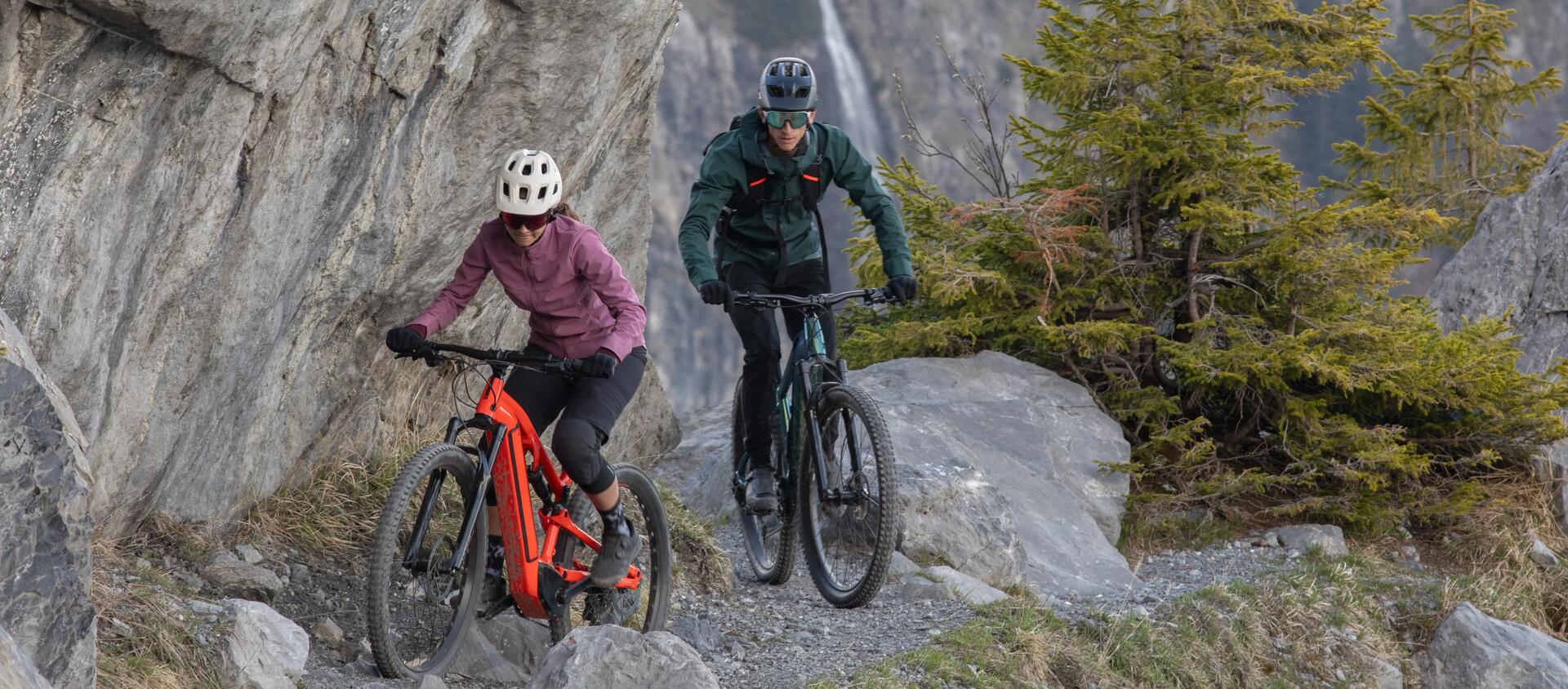 Un uomo e una donna in MTB su terreno sassoso in montagna.