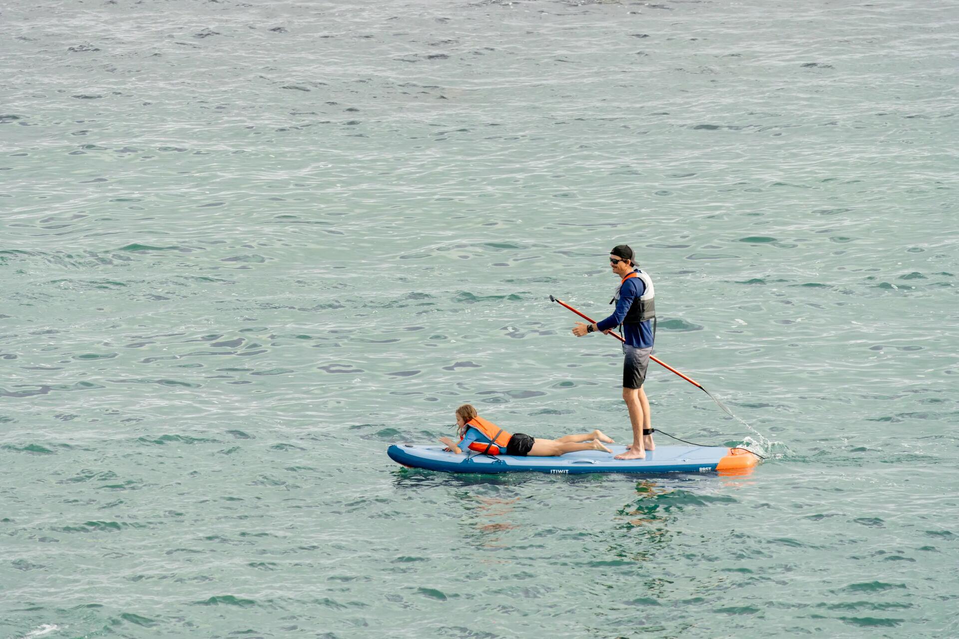 mężczyzna stojący na desce stand up paddle