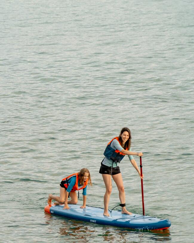 Zwei Menschen in Schwimmwesten auf einem blauen Paddleboard auf ruhigem Wasser.