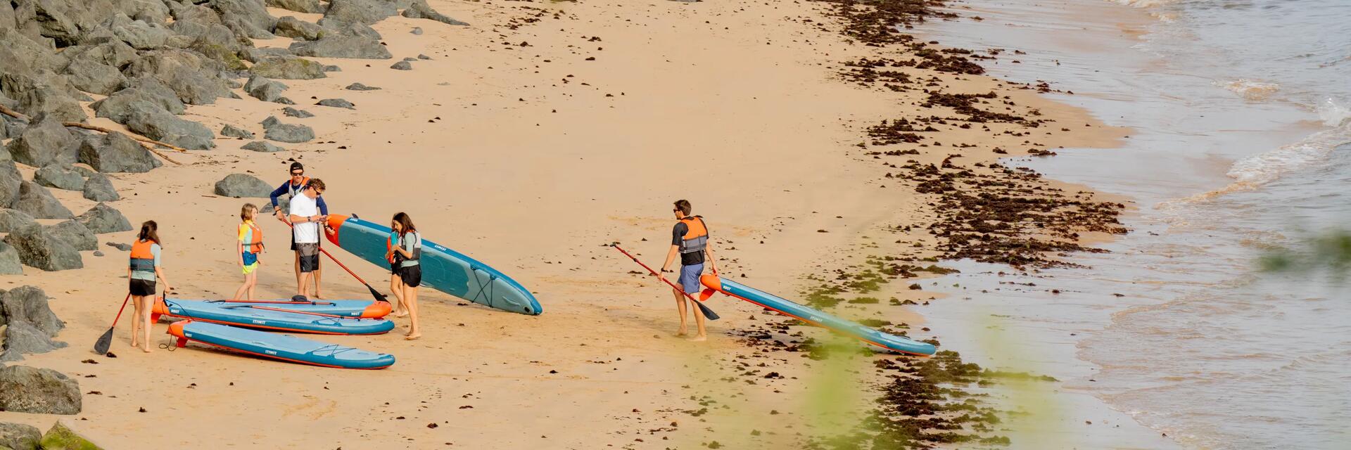 Freundesgruppe steht mit SUPs am Strand