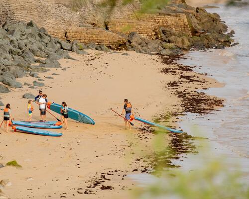 Freundesgruppe steht mit SUPs am Strand
