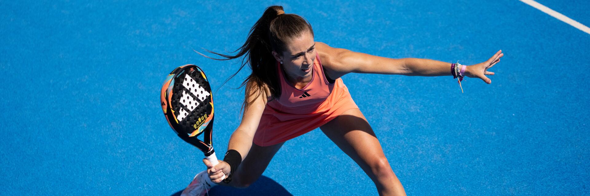 Eine Padel-Spielerin auf dem Court hält ihren Schläger bereit, um den Ball zu schlagenart