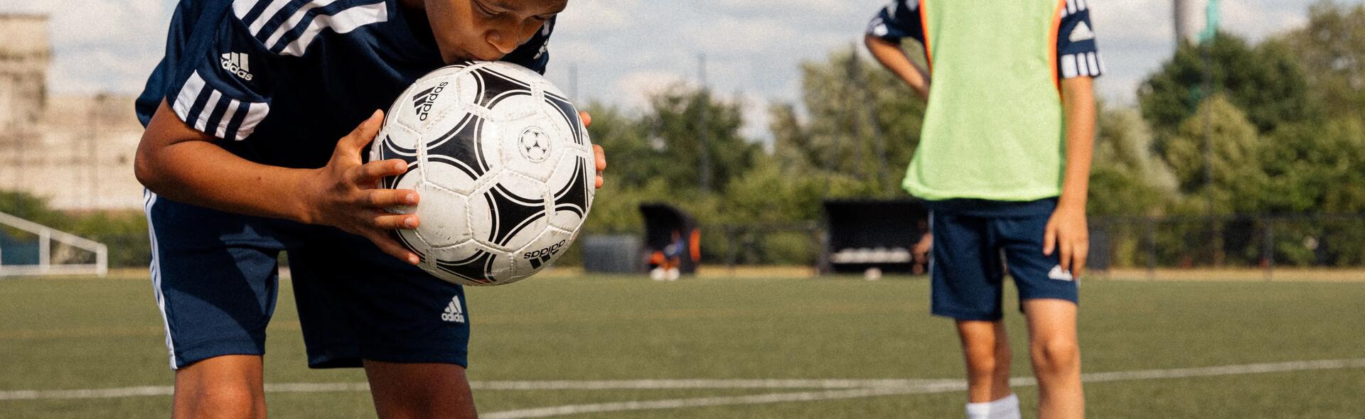 chłopiec w stroju piłkarskim trzymający piłkę do piłki nożnej