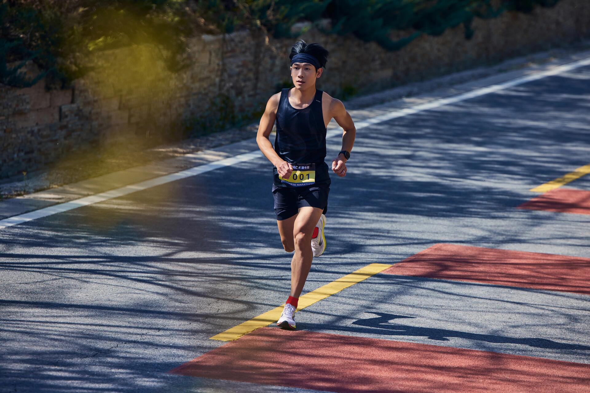 Mężczyzna w odzieży sportowej biegnący w maratonie po asfalcie