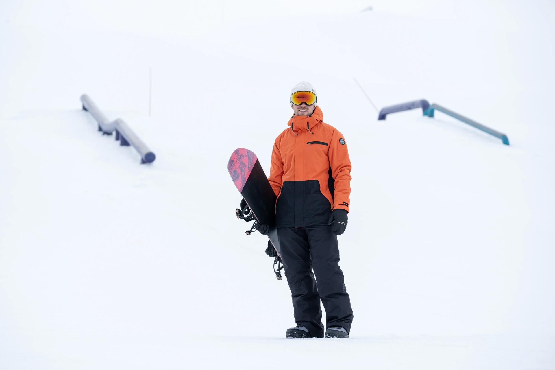Mężczyzna stojący z deską snowboardową w goglach