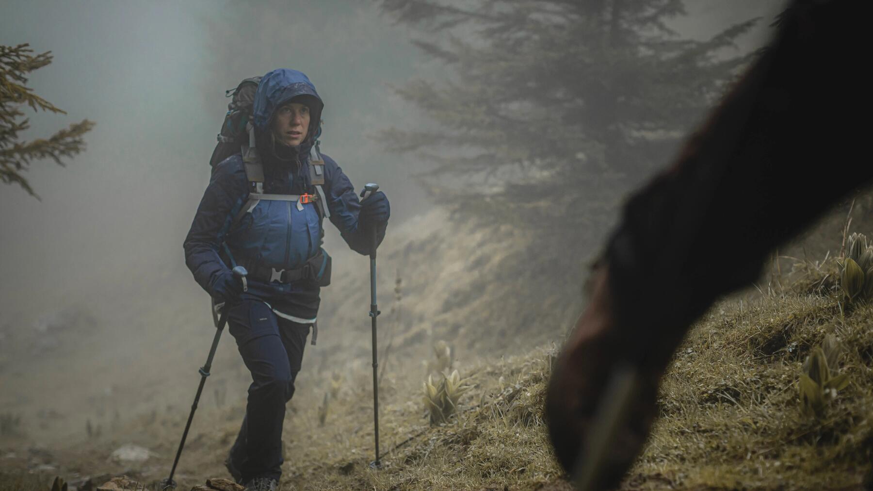 Eine Frau wandert mit Trekkingstöcken im Nebel
