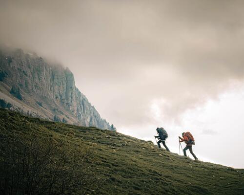 osoby wędrujące po górach z kijami trekkingowymi