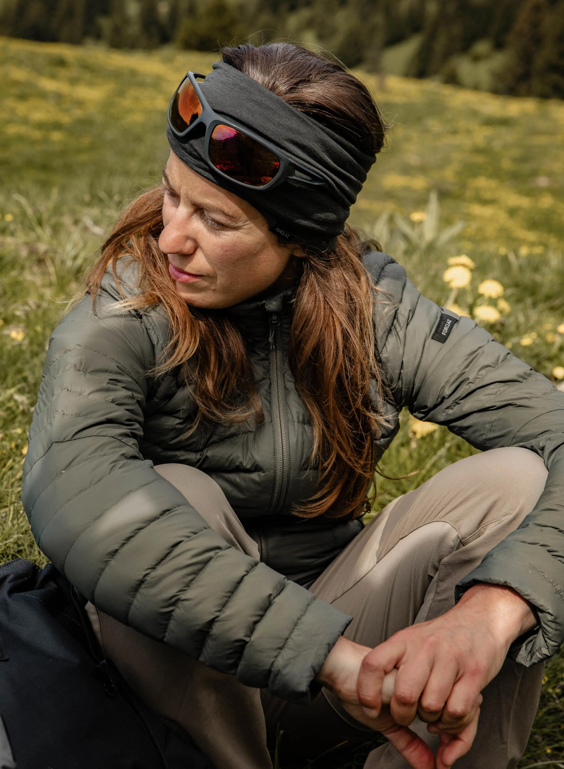 Kobieta w kurtce puchowej w trakcie trekkingu po górach