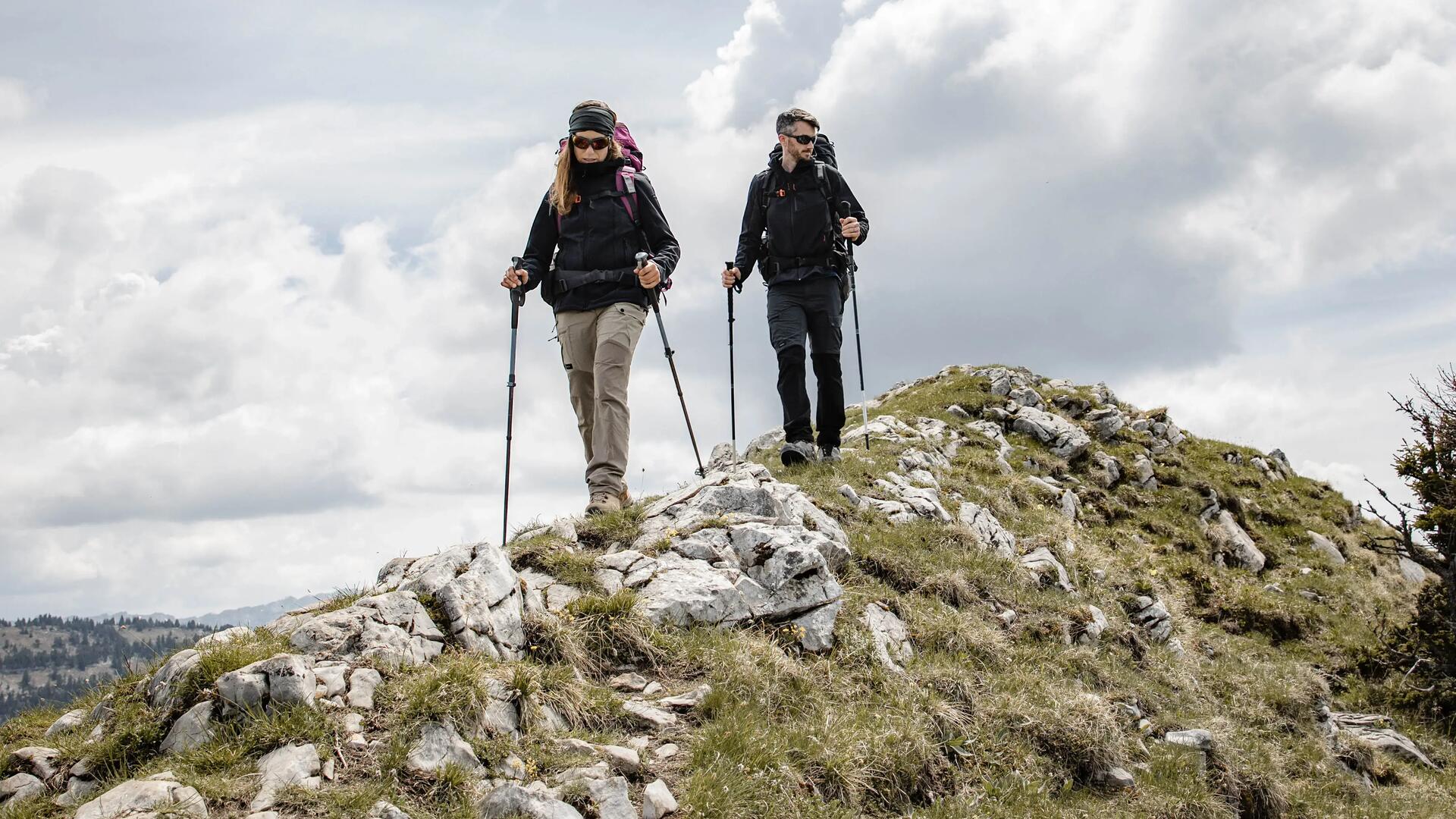 Para z plecakami wędrująca po górach z kijkami trekkingowymi