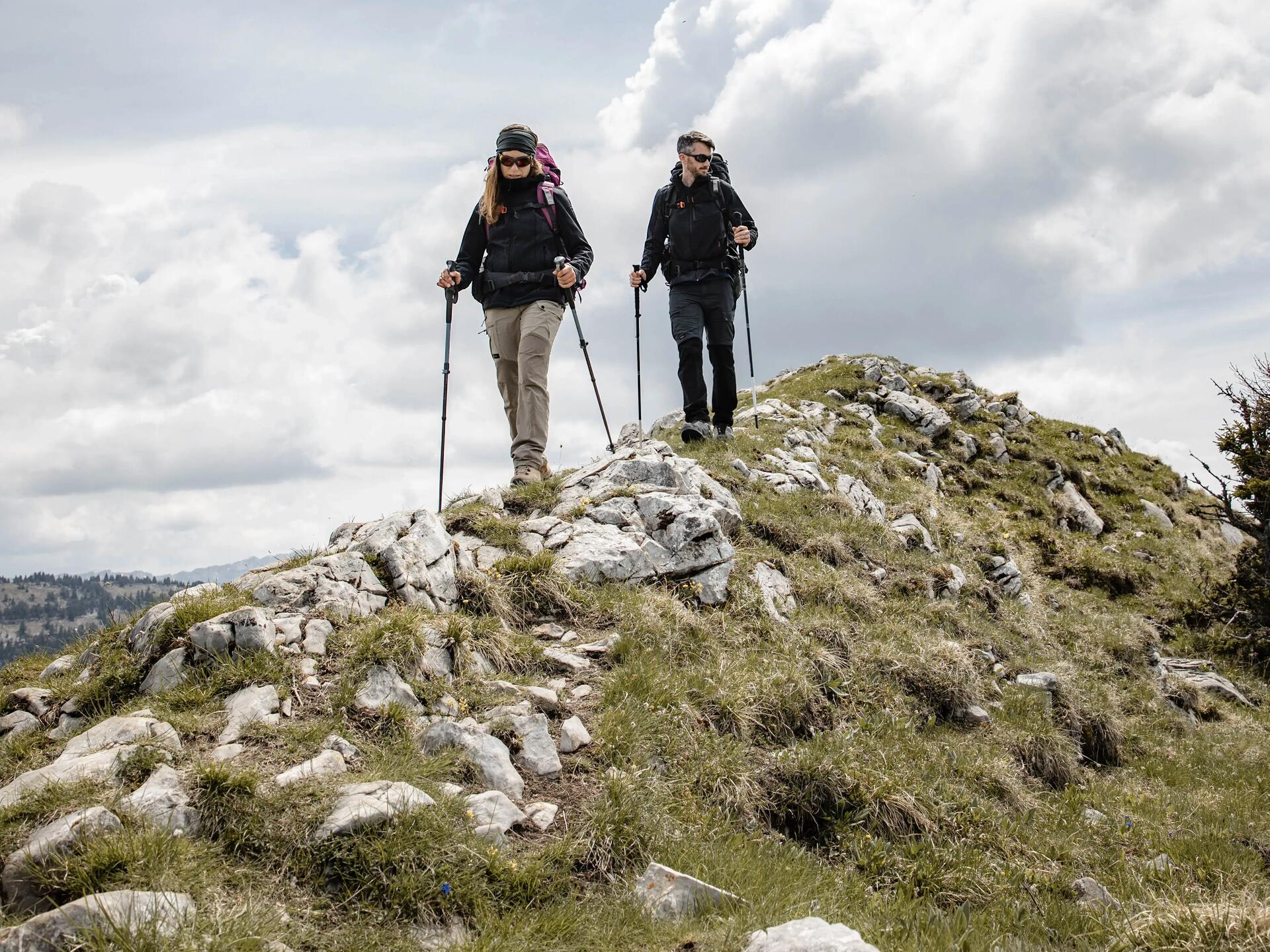 Para z plecakami wędrująca po górach z kijkami trekkingowymi