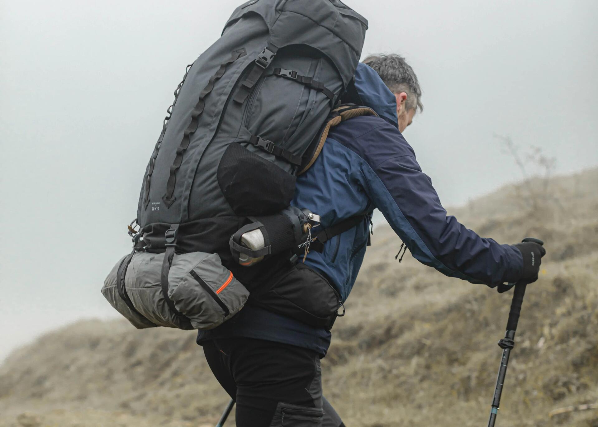 mężczyzna wędrujący z plecakiem turystycznym i kijkami trekkingowymi 