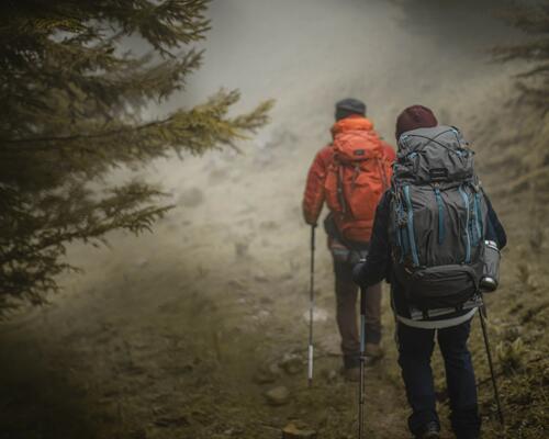 mężczyzna z plecakiem na plecach i kijem trekkingowym w ręce