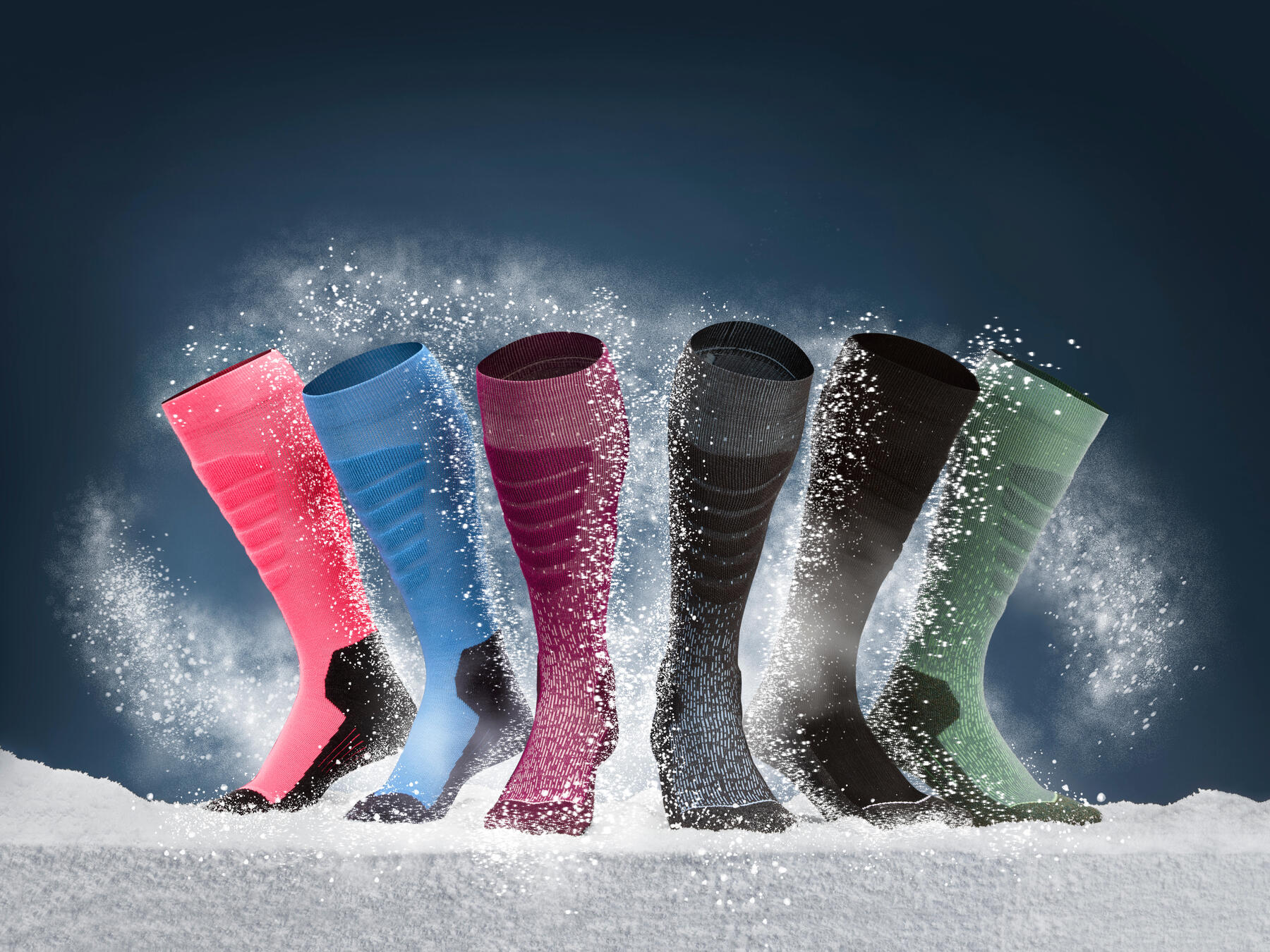 6 sokken in verschillende kleuren die in de sneeuw worden gepresenteerd.
