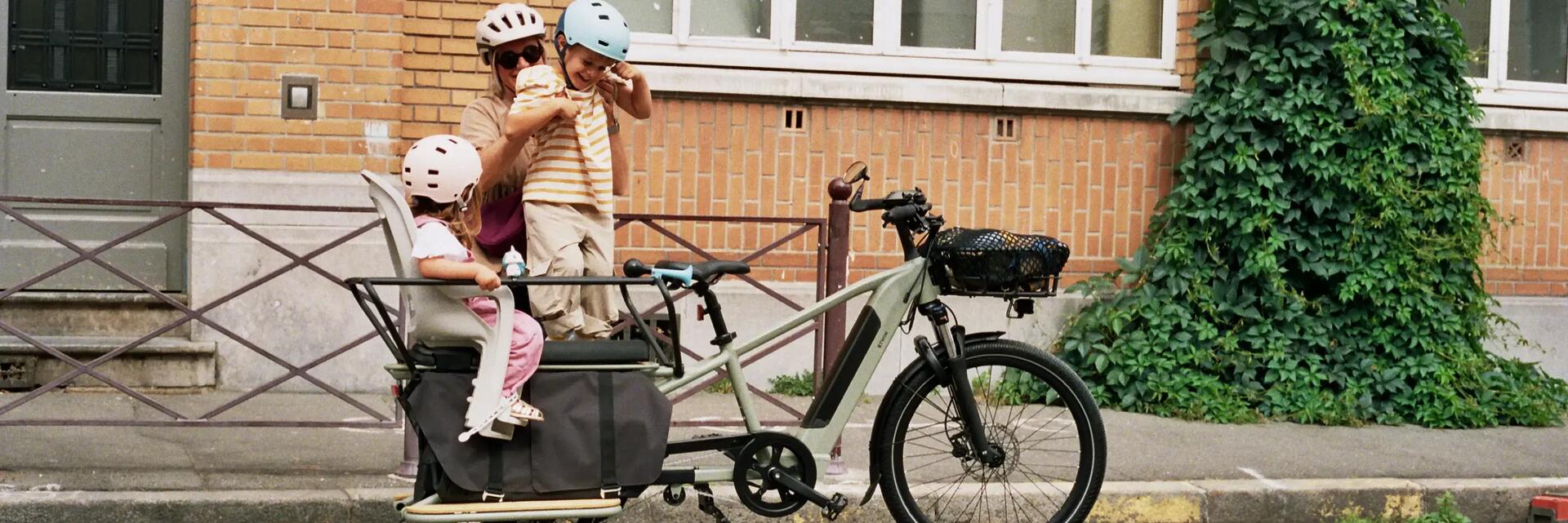 mama zet haar kinderen achterop de fiets
