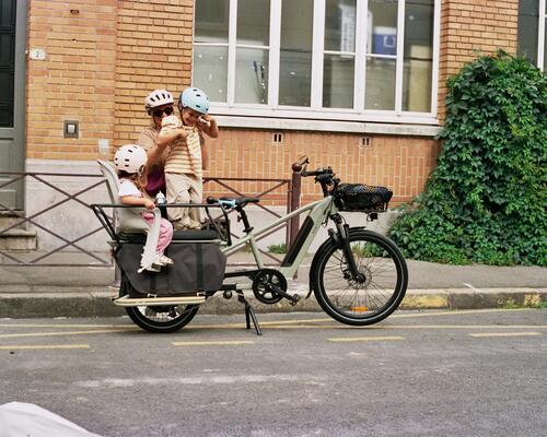 mama zet haar kinderen achterop de fiets