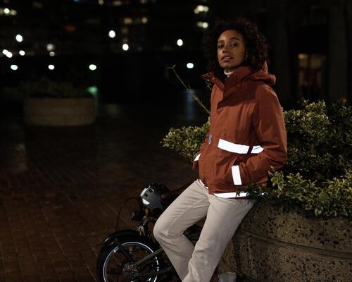 Eine Frau trägt nachts eine Winterjacke fürs Fahrrad