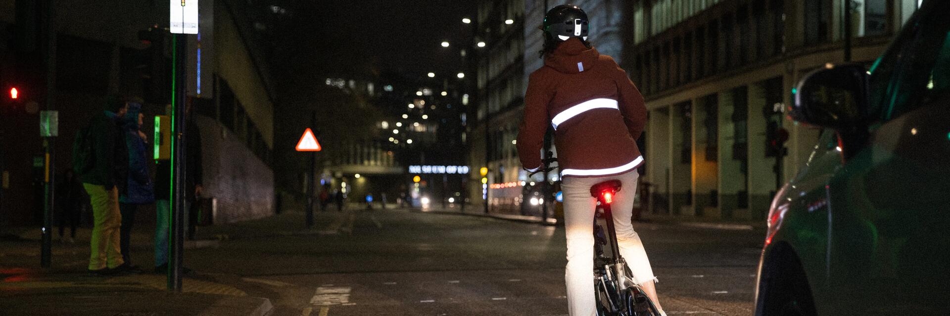 Kobieta jadąca na rowerze elektrycznym z włączonym tylnym oświetleniem