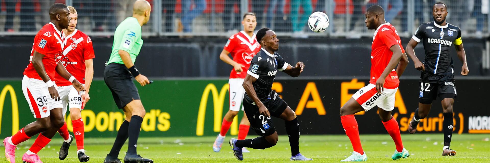 Ausschnitt eines Fußballspiels zwischen FC Valenciennes in rot-weiß und AJ Auxerre in schwarz.
