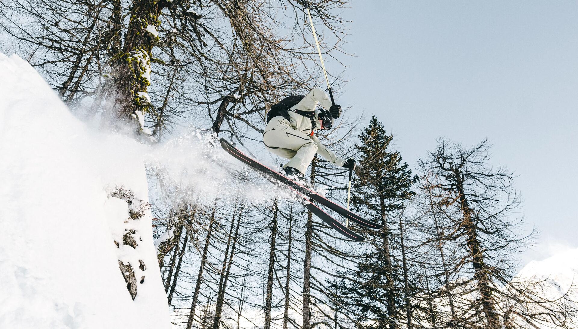 mężczyzna w kasku i goglach narciarskich skaczący na nartach poza trasą
