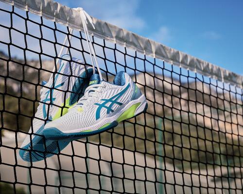 Tennisschuhe für den passenden Boden hängen am Netz