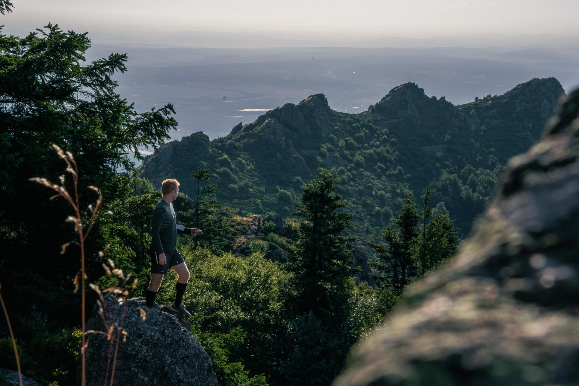 Mężczyzna w odzieży do fast hikingu stojący na skale w górach