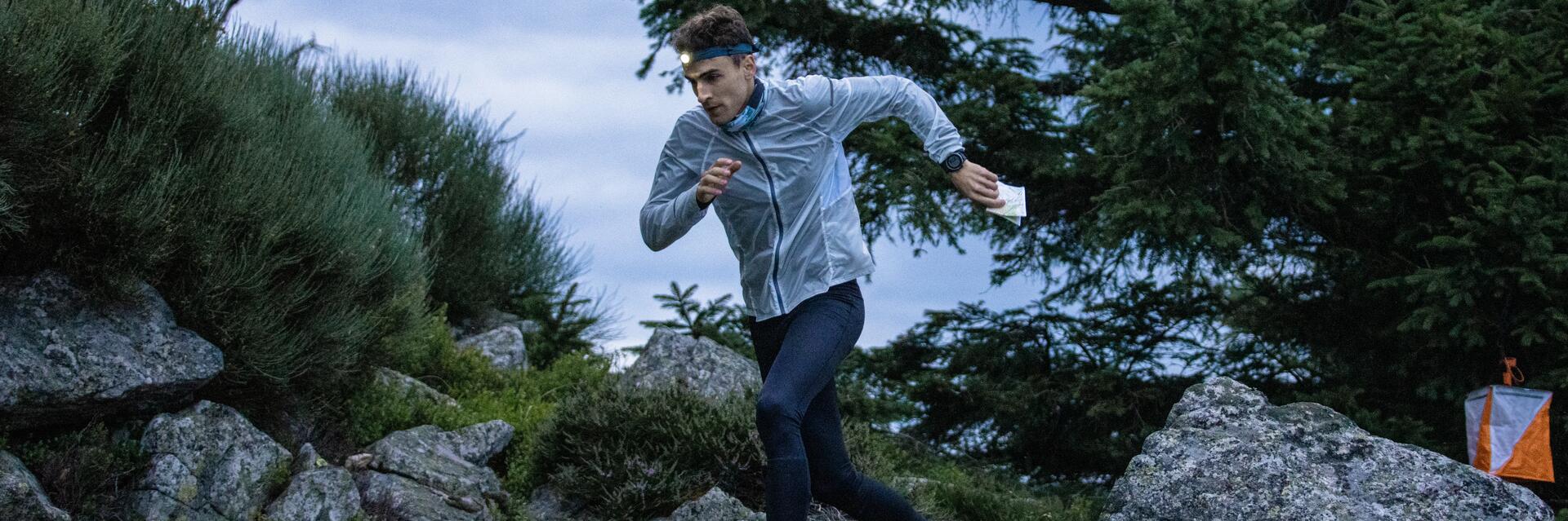 Mężczyzna z latarką czołową na głowie uprawiający speed hiking na górskim szlaku