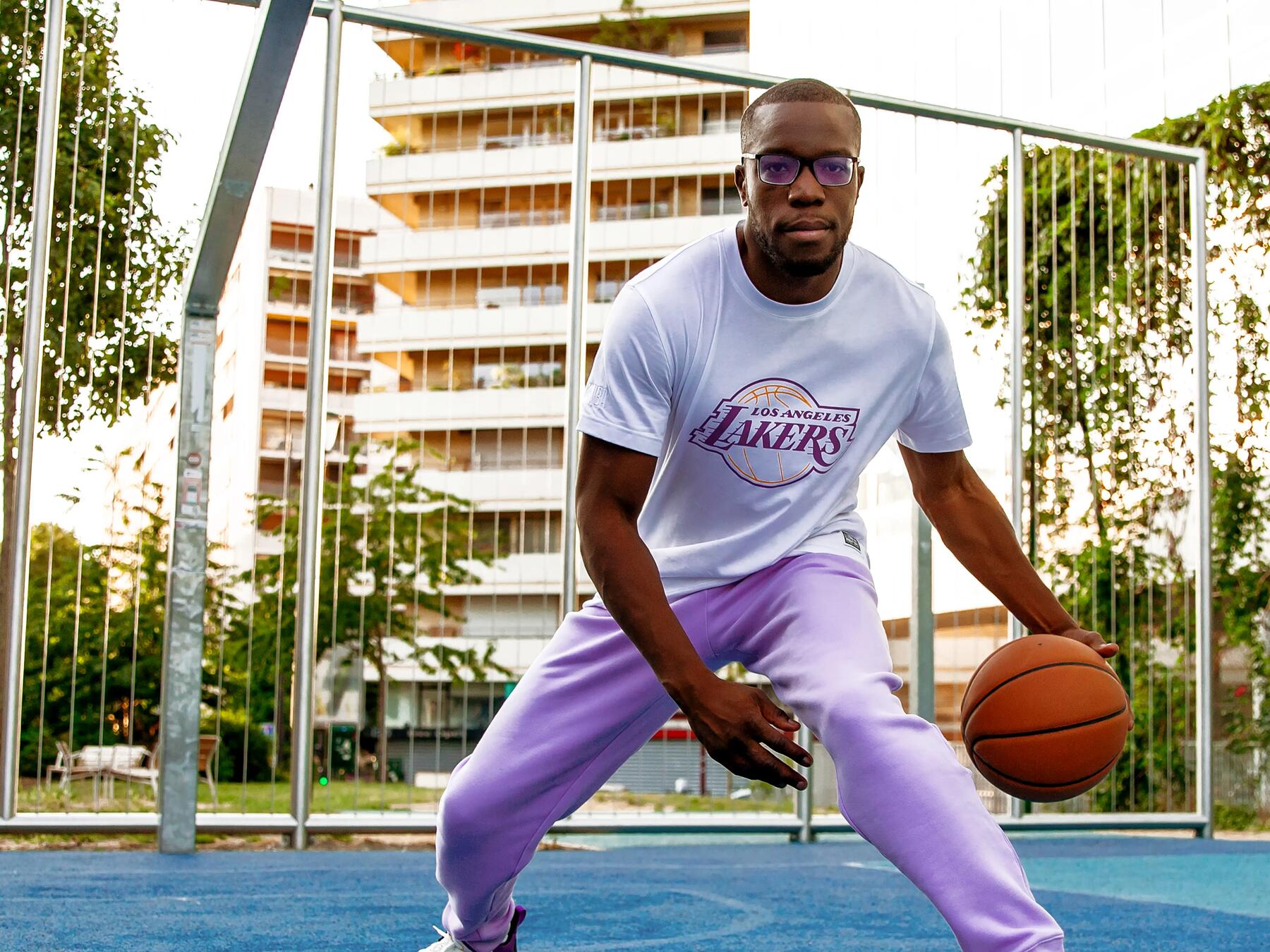 mężczyzna w odzieży sportowej  trzymający piłkę do koszykówki na boisku