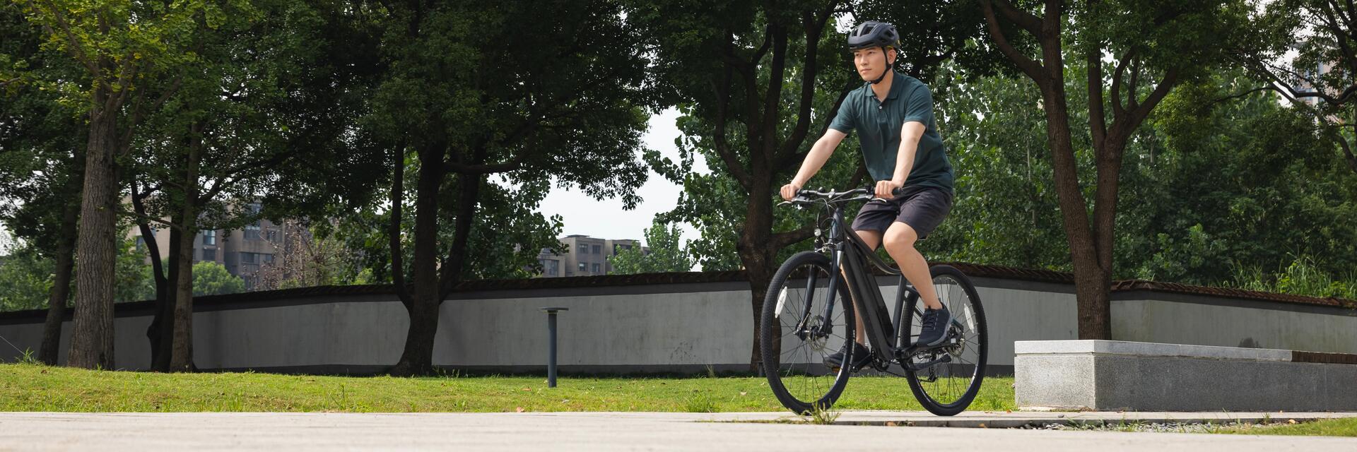Młody mężczyzna w kasku jadący rowerem przez park