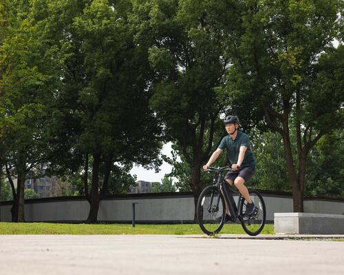 Młody mężczyzna w kasku jadący rowerem przez park