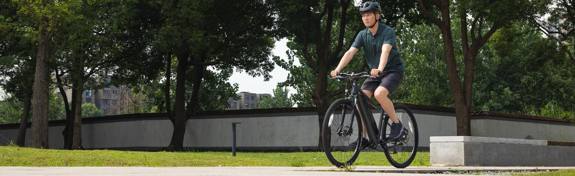 Młody mężczyzna jedzie na rowerze przez park w stroju sportowym i kaski