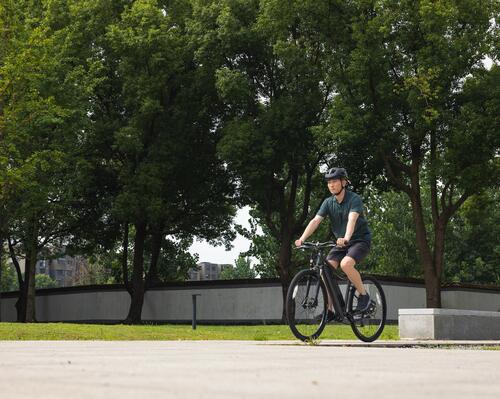 Młody mężczyzna jedzie na rowerze przez park w stroju sportowym i kaski