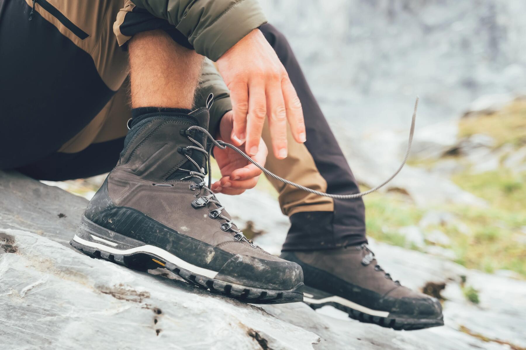 mężczyzna zawiązujący sznurówki w butach trekkingowych z wysoką cholewką