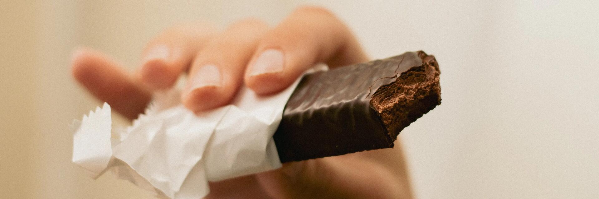 Osoba jedząca batonika czekoladowego podnosząca sobie poziom serotoniny w organiźmie