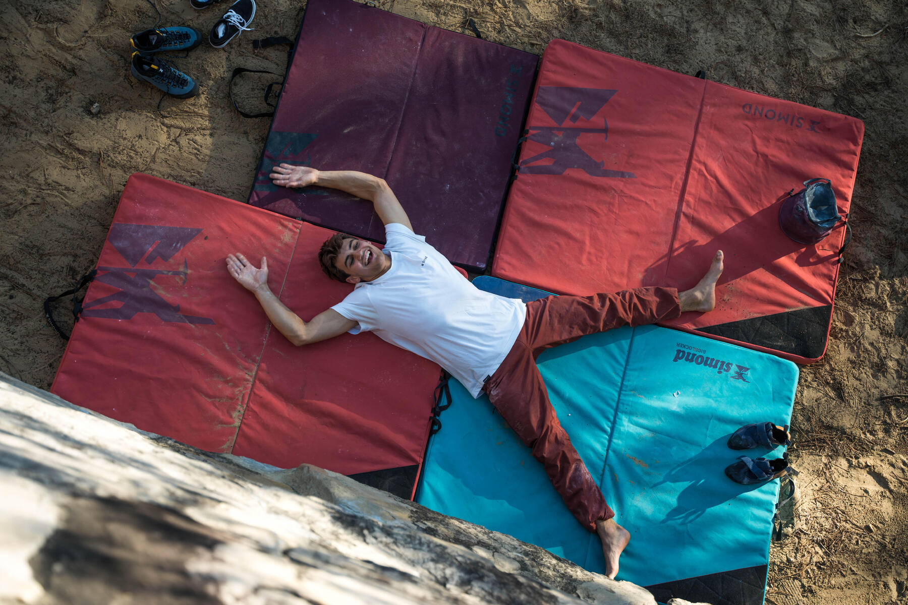 Eine Person liegt auf roten und blauen Boulder Matten. Er hat durch intensives Training abgenommen.