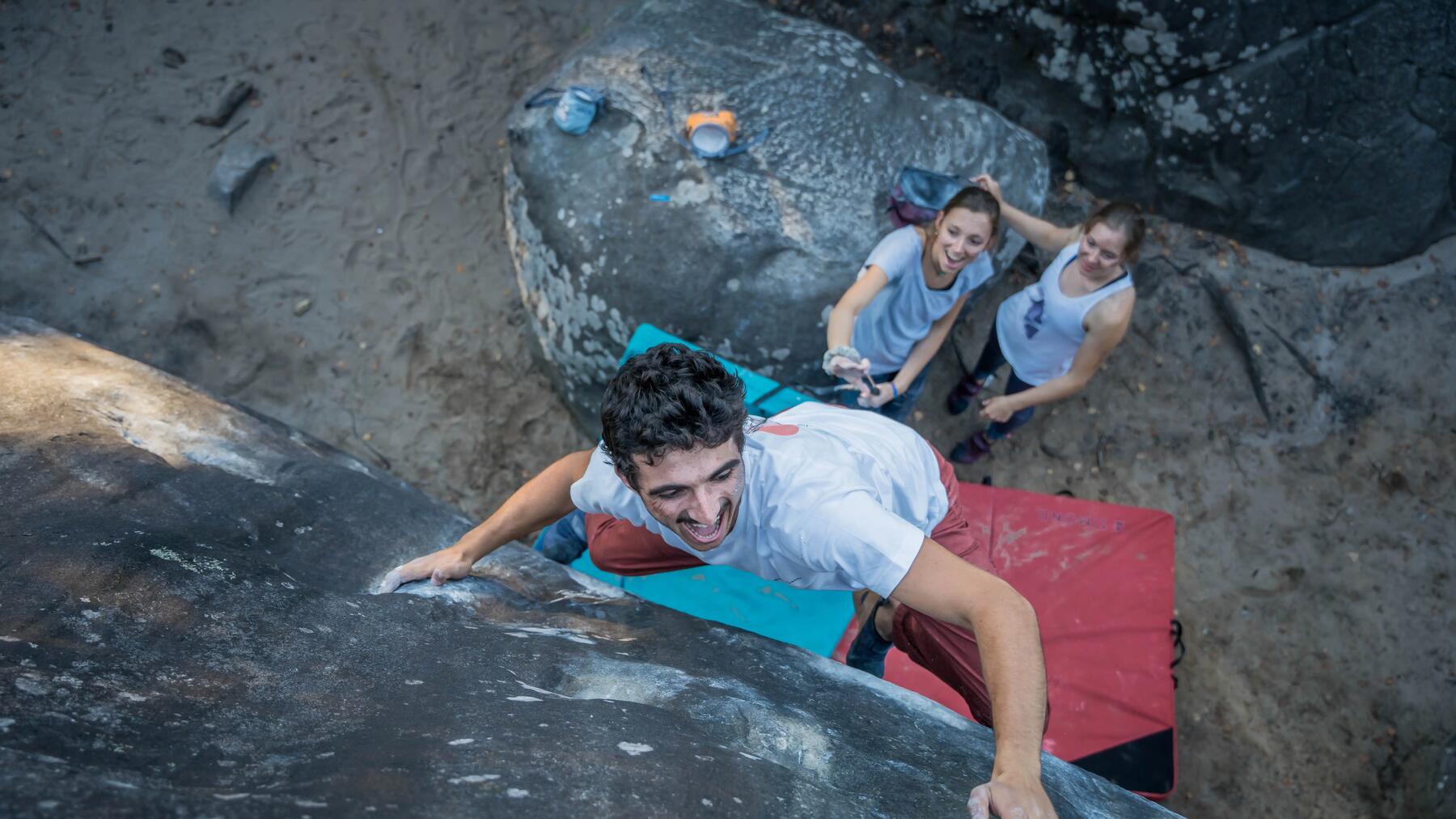 Eine Gruppe von Freunden nutzt beim Bouldern ein Crashpad