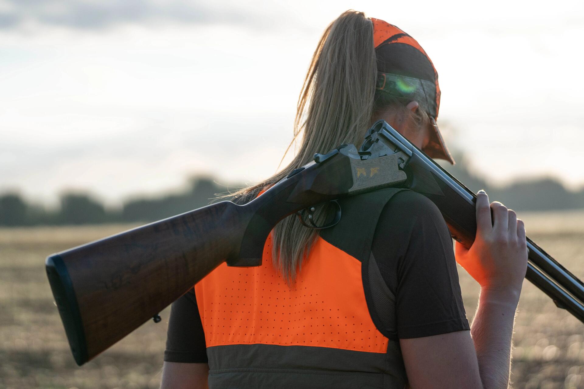 Une chasseresse avec son fusil à l'épaule partant chasser