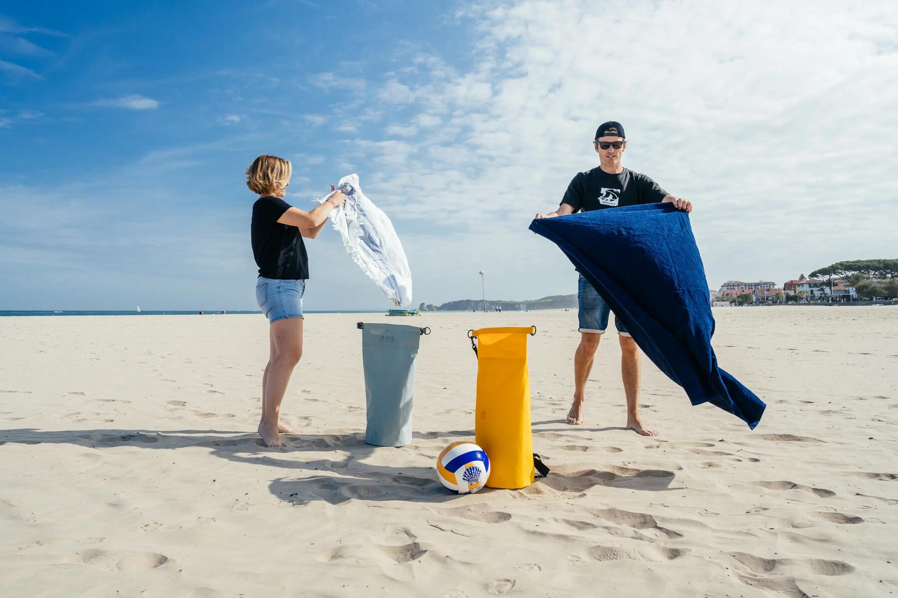 Man and woman packing away their beach towels in their dry bags