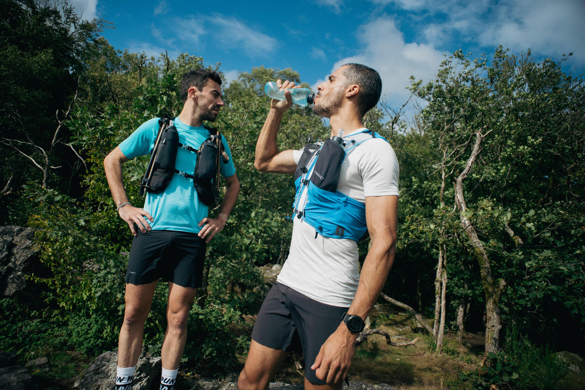 Mężcyzna w kamizelce biegowej nawadniający swój organizm podczas przygotowań do maratonu