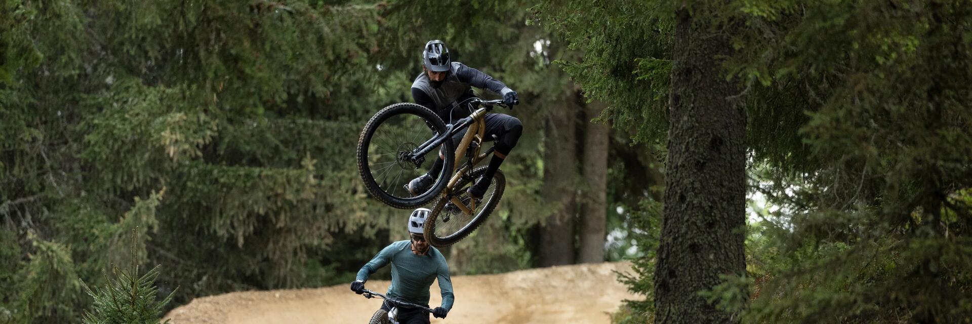 Mężczyźni jadący na rowerach MTB wykonujący na nich triki