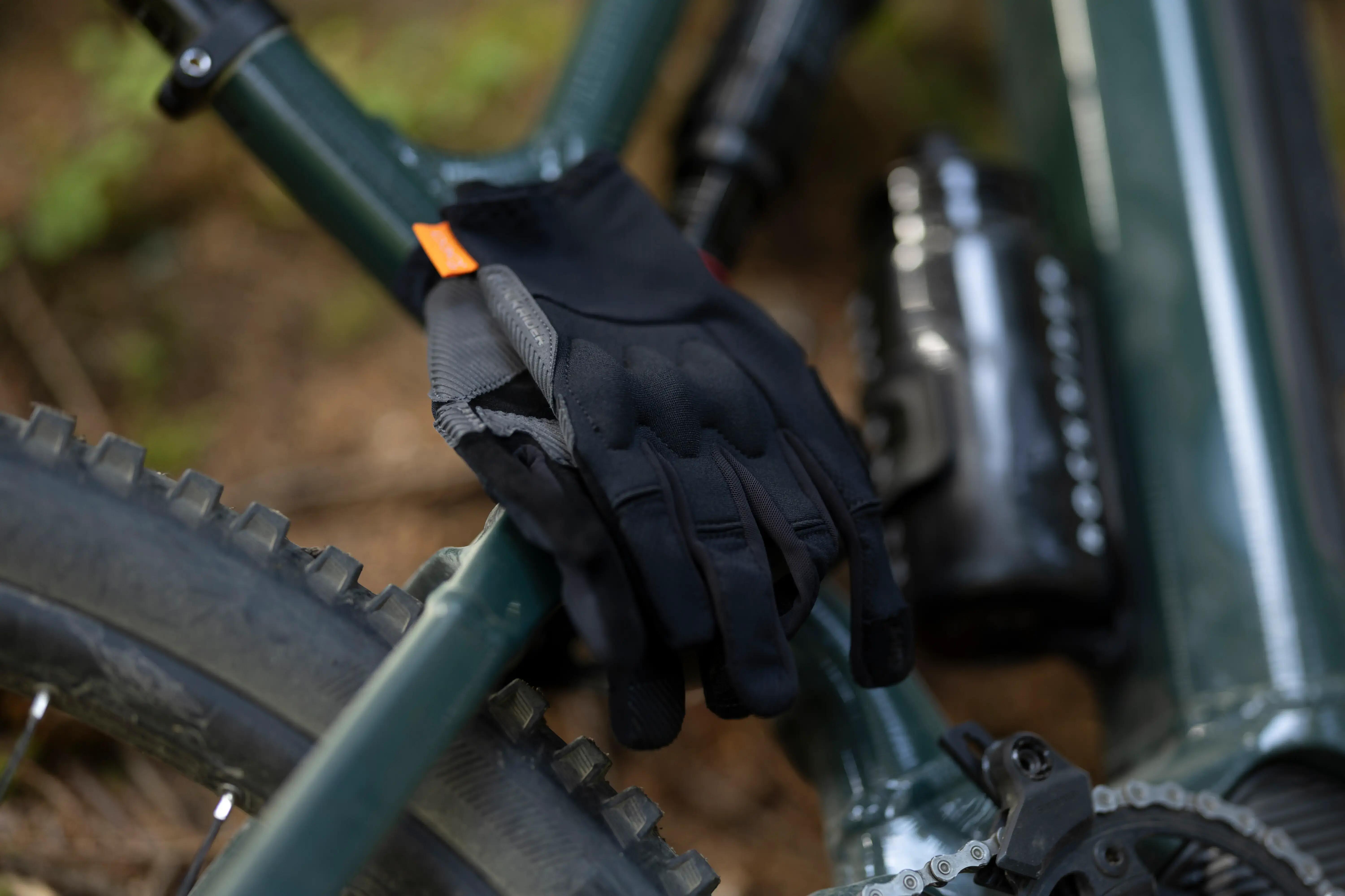 Black full-finger cycling gloves resting on a mountain bike frame