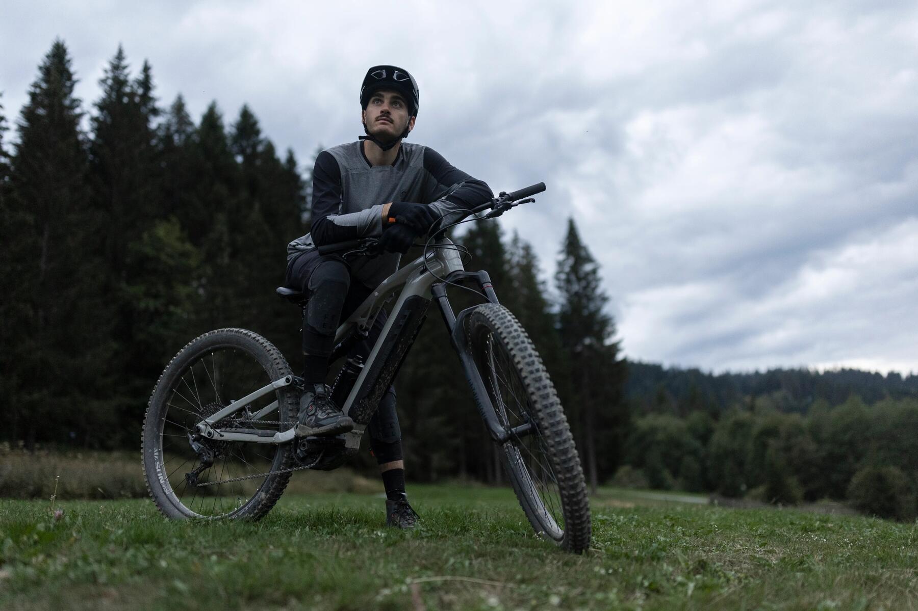 MTB-Fahrer lehnt entspannt auf dem Lenker seines Bikes