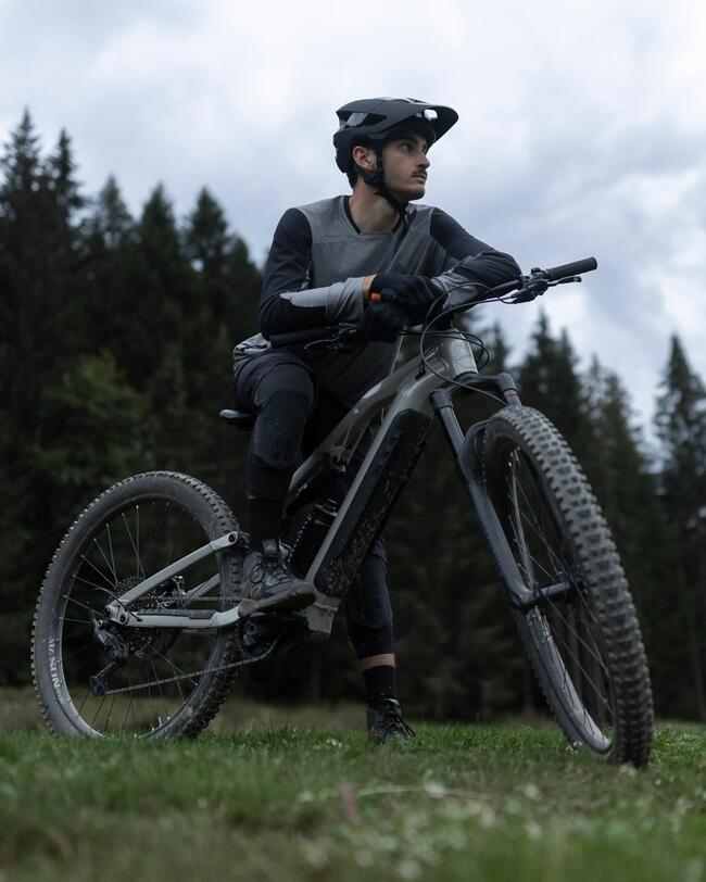 Mann auf E-Mountainbike sitzend und in die Ferne blickend