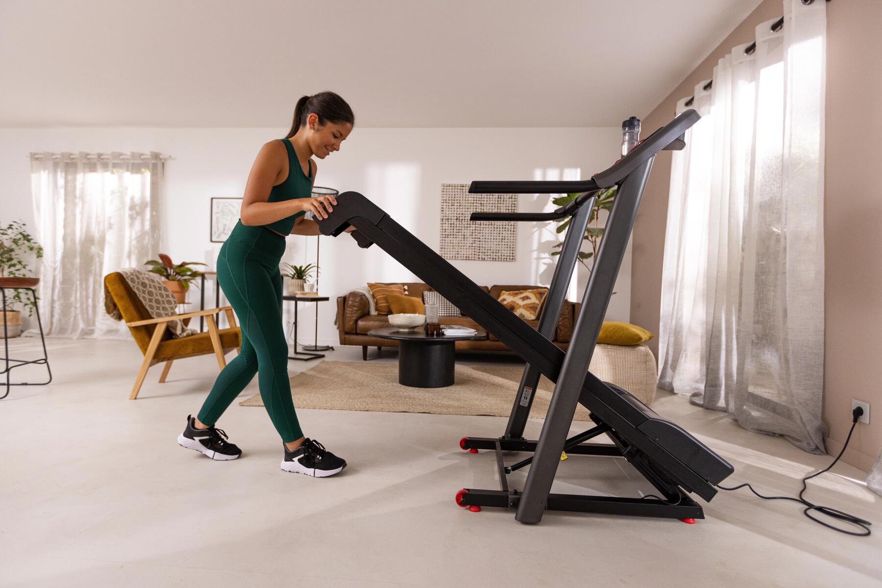 Kobieta w odzieży fitness rozkładająca bieżnię domową w celu nasmarowania pasa